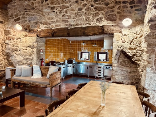 Stone cottage kitchen and dining area with modern stainless steel appliances and rustic wooden beams at Aconchego Rural