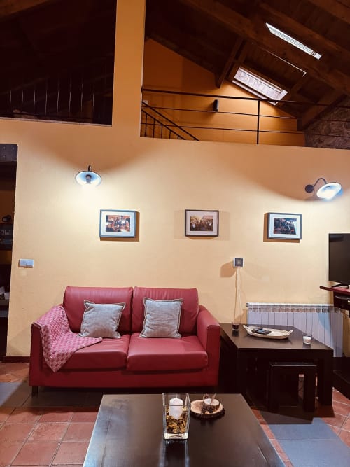 Cozy living room with red sofa, framed photos, and warm lighting at Aconchego Rural cottage in Montalegre