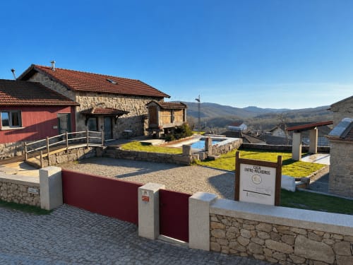 Casa Entre Palheiros rural cottage exterior with stone architecture, private pool, and mountain views in Sezelhe, Portugal