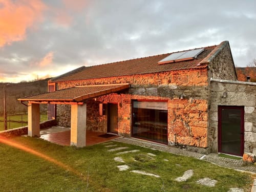 Stone cottage at Aconchego Rural with terracotta tile roof, covered patio, and mountain views at sunset in Sezelhe,