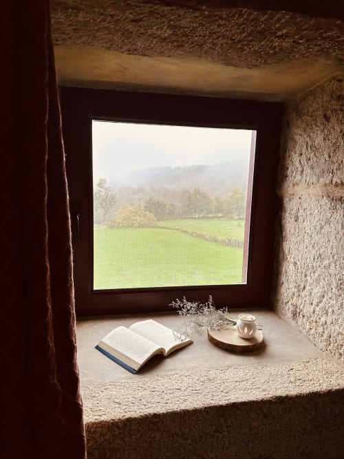 Cozy window nook at Aconchego Rural cottage overlooking green valley and mountains in Montalegre, Portugal