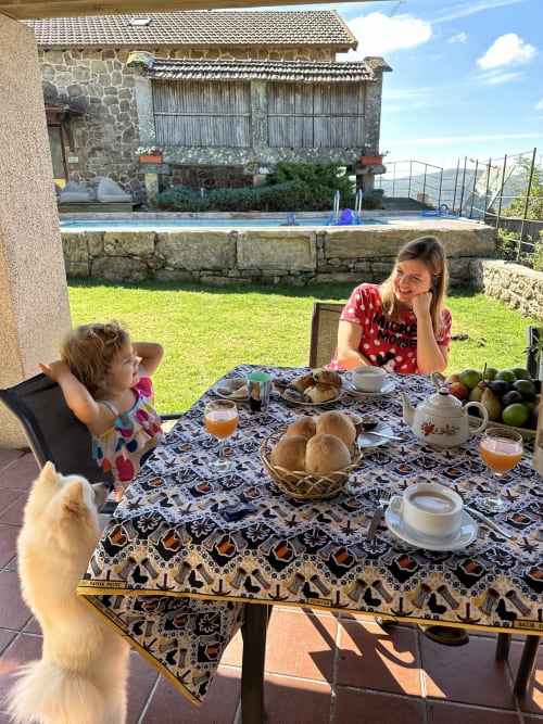 Woman and child enjoying breakfast at outdoor table with mountain views at Aconchego Rural cottage, Portugal