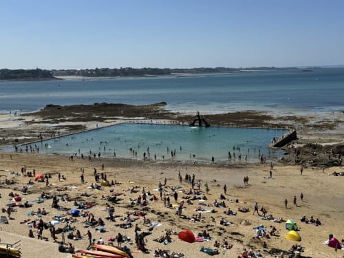 Busy beach day at Les Vieilles Digues in Beauvoir with turquoise tidal pool, sandy shore, and coastal scenery