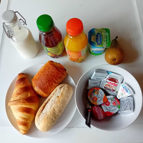 Petit-déjeuner continental aux Petits Nids De Nina : croissants, baguette, lait, jus de fruit, fruits et confitures.