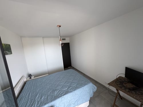Chambre de l'appartement Conciergerie De Porticcio avec lit, armoire coulissante, luminaire suspendu, TV et mobilier contemporain