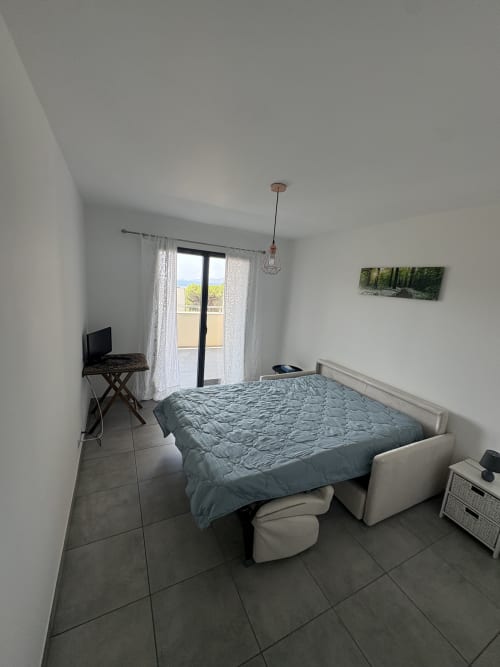 Chambre moderne dans l'appartement de Porticcio avec balcon vue mer, lit, bureau TV et carrelage