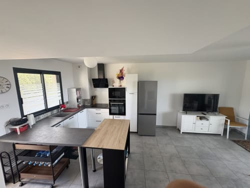 Cuisine ouverte moderne et séjour dans l'appartement de Porticcio avec électroménagers inox, îlot de repas et vue sur mer