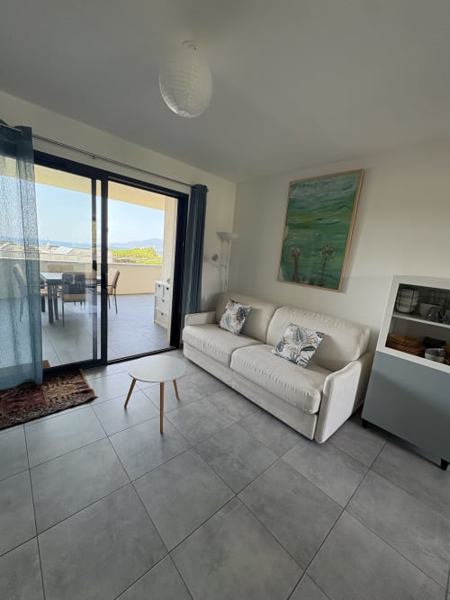 Séjour lumineux avec canapé crème, terrasse vue mer et équipements modernes à la Conciergerie De Porticcio, Corse