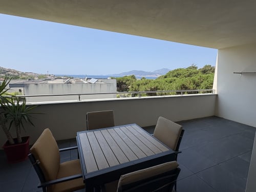 Terrasse spacieuse à la Conciergerie De Porticcio avec table à manger, vue mer sur Porticcio, les montagnes de Corse