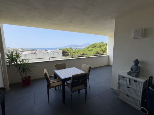 Balcon avec vue sur mer à l'appartement Conciergerie De Porticcio, table à manger, chaises et panorama montagneux
