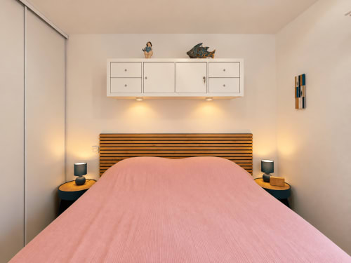 Chambre moderne de l'appartement de Calvi avec literie rose, tête de lit en bois et éclairage ambiant près de L'Île-Rousse