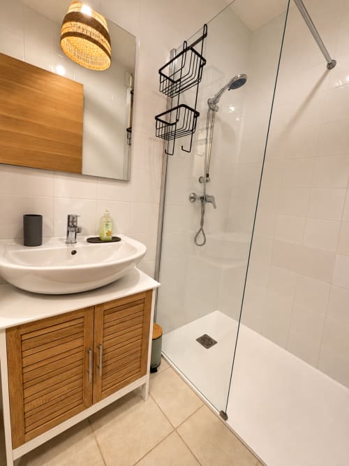 Salle de bain moderne avec douche à l'italienne, vasque ronde, meuble en bois et lampe suspendue en rotin à L'Île-Rousse