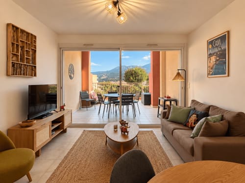 Séjour moderne et lumineux à Calvi avec vue sur les montagnes, mobilier confortable, TV et accès à la terrasse