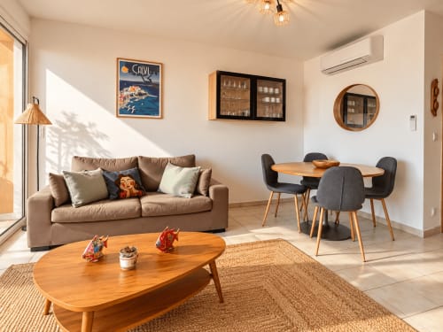 Séjour lumineux avec canapé beige, table en bois et mobilier contemporain dans un appartement à Calvi près du centre de L'Île-Rousse