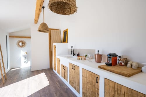 Kitchenette moderne avec placards en bois, plan de travail blanc et suspensions tissées au Domaine Mas Lafleur, Châteaurenard