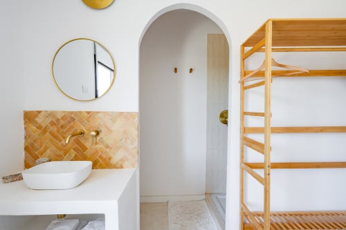 Salle de bain moderne au Domaine Mas Lafleur avec vasque, robinetterie en laiton, carrelage géométrique et étagères bois