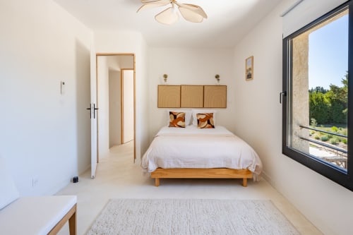 Chambre lumineuse au Domaine Mas Lafleur à Châteaurenard avec lit en bois, grandes fenêtres donnant sur les jardins et design moderne