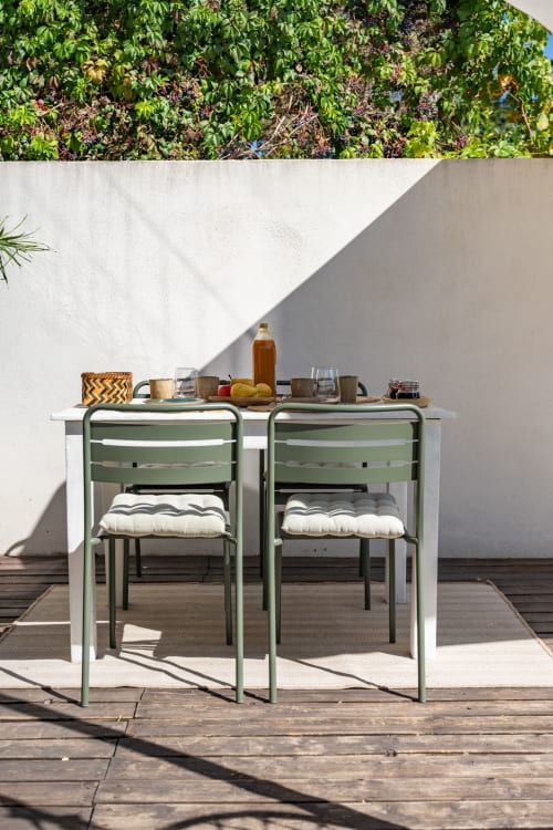 Coin repas en plein air à la villa Domaine Mas Lafleur avec chaises vertes, table blanche et rafraîchissements vue sur les jardins luxuriants
