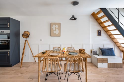 Salle à manger moderne de la Villa Lafleur au Domaine Mas Lafleur, Châteaurenard, avec table en bois, chaises tressées et escalier.