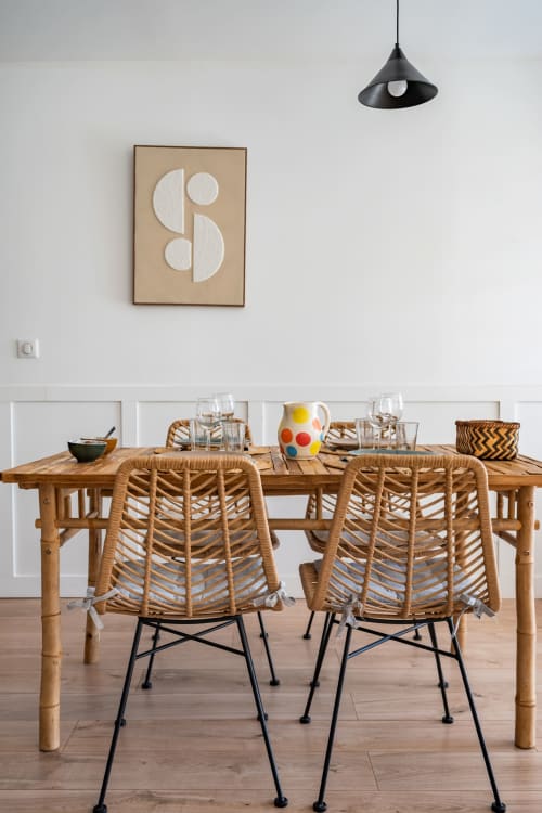 Salle à manger contemporaine à Domaine Mas Lafleur avec chaises tressées, table en bois, art géométrique mural et lampe suspendue.