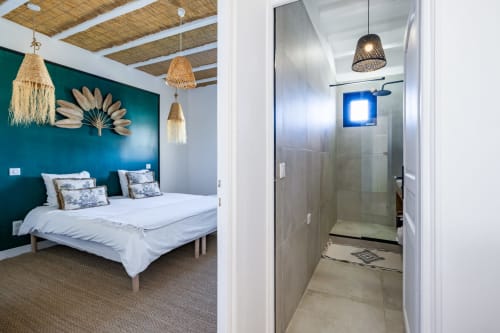 Chambre de la villa Domaine Mas Lafleur avec mur d'accent bleu-vert, suspensions tissées et salle de bain attenante avec douche à l'italienne