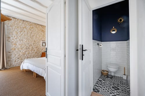 Chambre et salle de bains Domaine Mas Lafleur aux murs blancs, carrelage à motifs et accent mur bleu marine à Châteaurenard