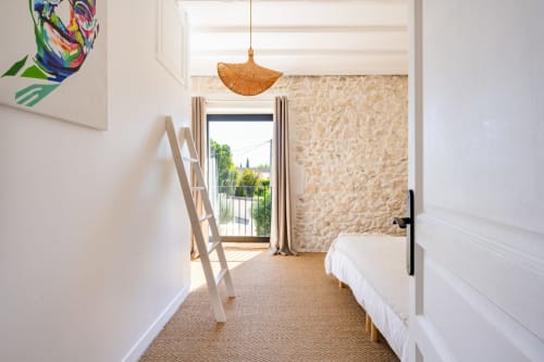 Chambre moderne au Domaine Mas Lafleur à Châteaurenard avec lit blanc, luminaire pendant tissé et accès terrasse