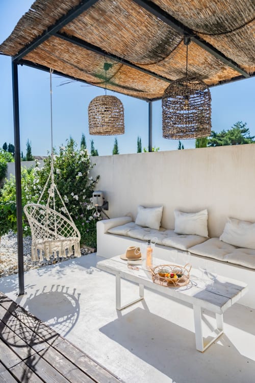 Terrasse élégante du gîte Domaine Mas Lafleur avec voile d'ombrage, luminaires suspendus, mobilier lounge blanc et