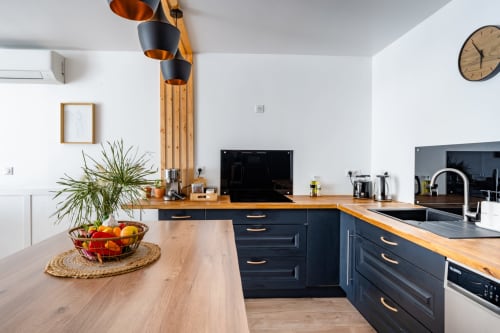 Cuisine moderne au Domaine Mas Lafleur à Châteaurenard : meubles sombres, plan de travail bois et luminaires suspendus