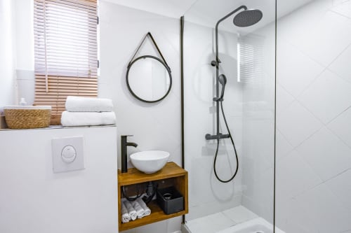 Salle de bain moderne du gîte Domaine Mas Lafleur à Châteaurenard avec douche pluie, vasque en bois et miroir rond