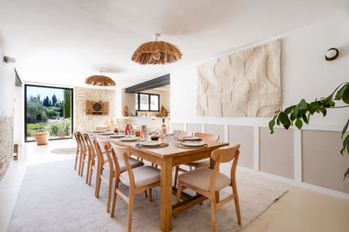 Salle à manger lumineuse de la villa Domaine Mas Lafleur avec table en bois, luminaires suspendus tissés et vue sur le jardin