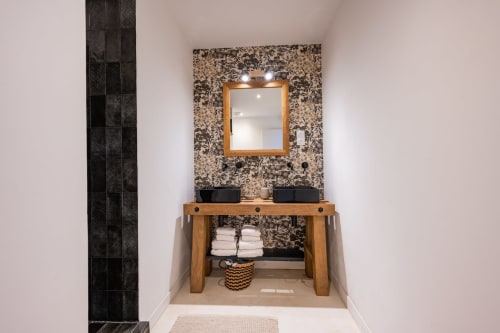 Salle de bains moderne au gîte Domaine Mas Lafleur avec meuble-vasque en bois, doubles vasques noires et décoration florale