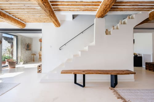 Intérieur minimaliste lumineux au Domaine Mas Lafleur avec poutres en bois, murs blancs, banc rustique et escalier