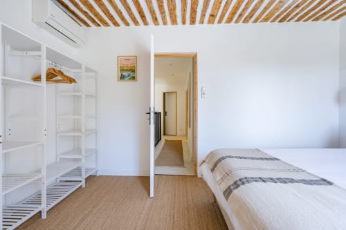 Chambre moderne au Domaine Mas Lafleur B&B à Châteaurenard avec lit, étagères blanches, plafond en bois et entrée salle de bain.