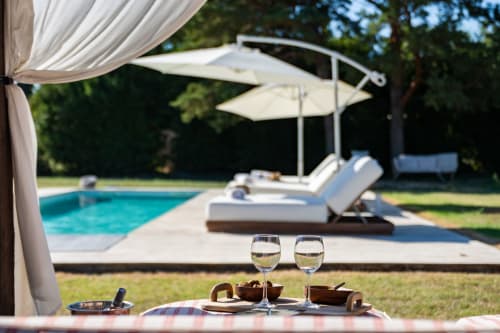 Repas en bord de piscine au Domaine Mas Lafleur avec verres de vin blanc, parasols et transats face à la piscine