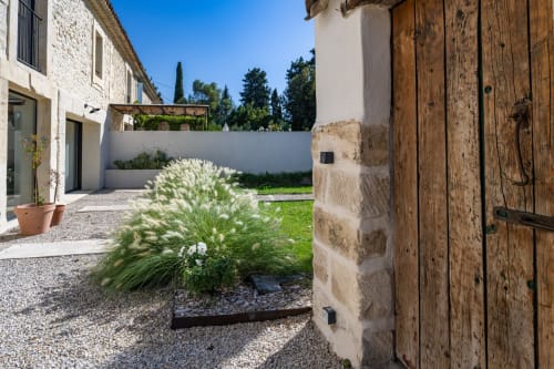 Jardin de cour du Domaine Mas Lafleur à Châteaurenard avec bâtiments en pierre, herbes ornementales et ambiance méditerranéenne