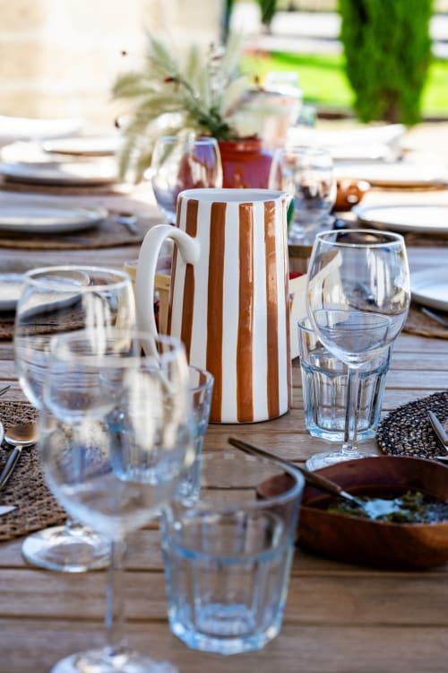 Table de restaurant en plein air au Domaine Mas Lafleur avec pichet rayé, verres d'eau et couverts à Châteaurenard