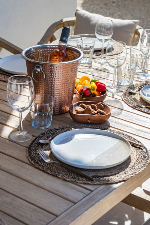 Table de repas en plein air à Domaine Mas Lafleur avec bouteille de vin, verres, assiette blanche et poivrons frais à Châteaurenard