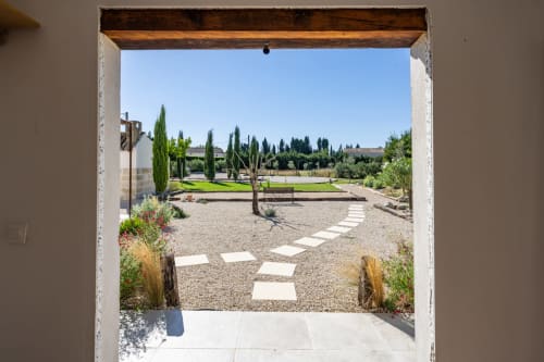 Vue de la chambre de Domaine Mas Lafleur avec jardins paysagés, cyprès et allées de gravier à Châteaurenard