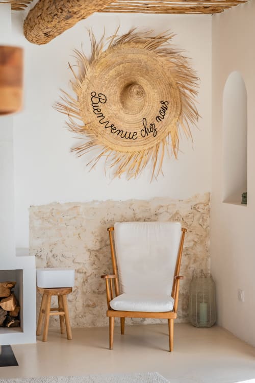 Coin salon cosy à Domaine Mas Lafleur avec chaise en bois, chapeau tressé sur le mur et mur en pierre