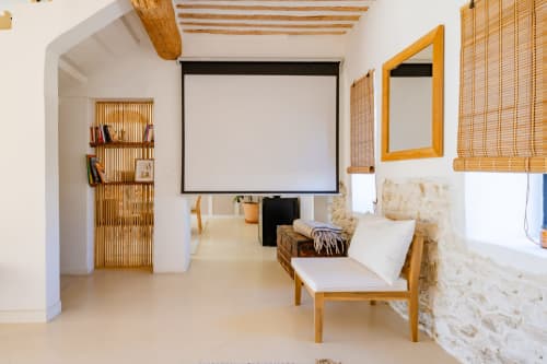 Chambre moderne avec poutres en bois, écran de projection et mur en pierre à Domaine Mas Lafleur
