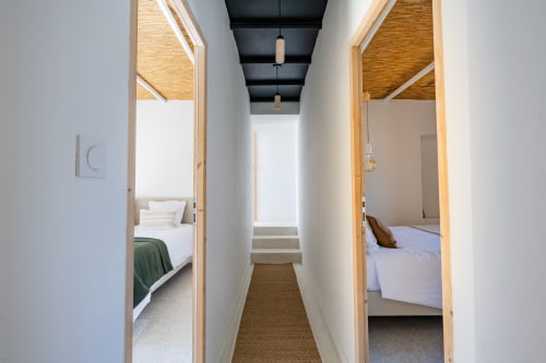 Couloir avec vue sur les chambres d'hôtes de Domaine Mas Lafleur, Châteaurenard, portes ouvertes sur les lits et luminaires suspendus