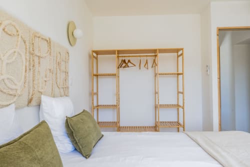 Chambre lumineuse au Domaine Mas Lafleur avec armoire en bois, lit blanc, coussins verts et décoration minimaliste à Châteaurenard