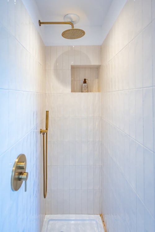 Douche moderne aux carrelages blancs, robinetterie dorée et pommeau de douche pluie au Domaine Mas Lafleur, Châteaurenard