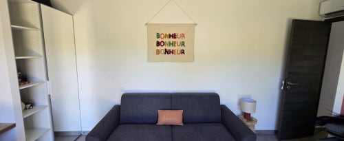 Salon moderne avec canapé bleu foncé, étagères murales et tableau 'Bonheur' à Villa Louniceli aux Villas d'A