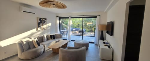 Salon moderne de villa aux Villas d'A Storia, Porto-Vecchio, avec canapé courbe, baies vitrées vue piscine et style contemporain