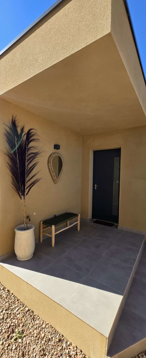 Terrasse de villa moderne aux Villas d'A Storia avec murs crème, porte noire, plante en pot, banc et art mural décoratif