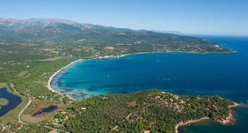 Vue aérienne de la baie turquoise de Pinarellu avec montagnes et littoral forestier près des Villas d'A Storia