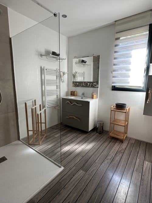Salle de bain moderne de la Villa Maé aux Villas d'A Storia avec douche, lavabo, étagères en bois et sèche-serviettes électrique