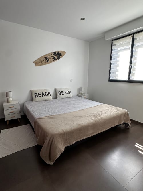 Chambre moderne lumineuse avec coussins aux thèmes marins, décoration murale en planche de surf et vue sur mer aux Villas d'A Storia, Ghisonaccia